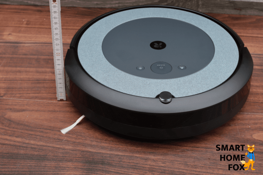 Measuring the height of an iRobot Roomba vacuum robot with a ruler.